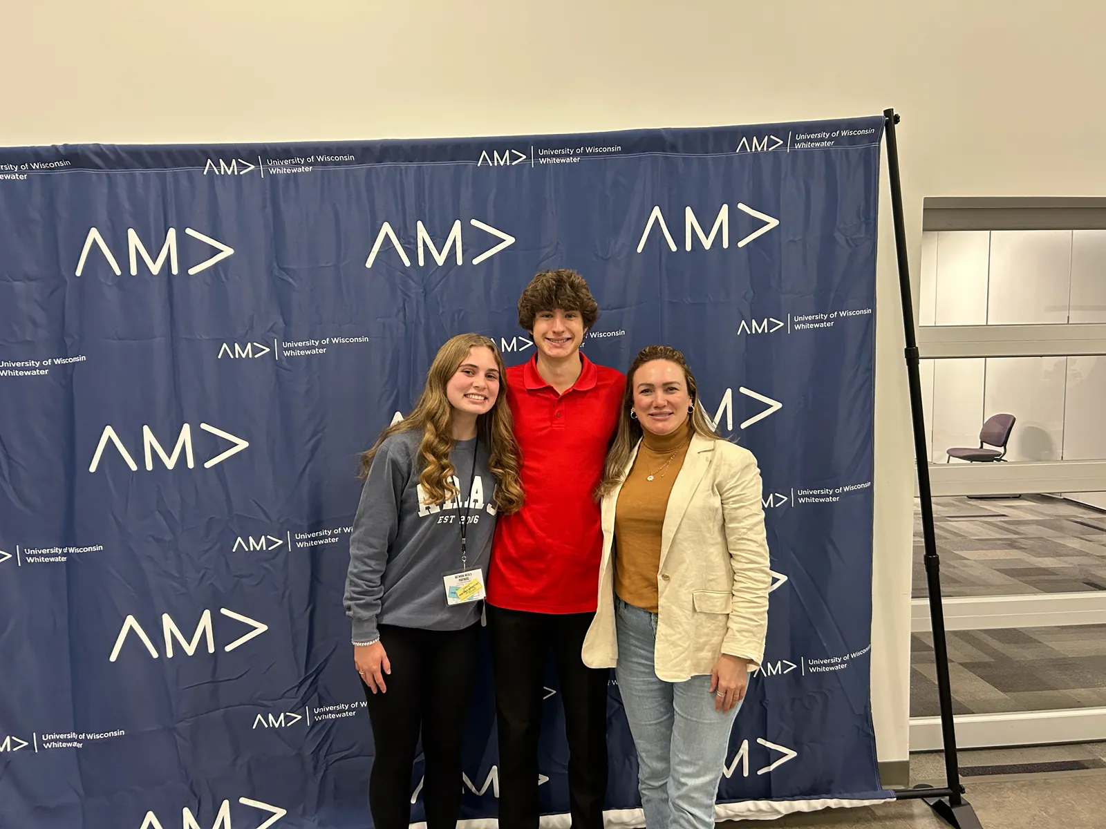 Three attendees in front of the AMA backdrop, photographed the Thursday evening before the conference.